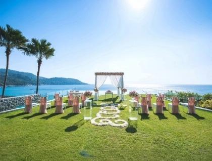 Outdoor wedding altar with pink chairs on lawn facing ocean view